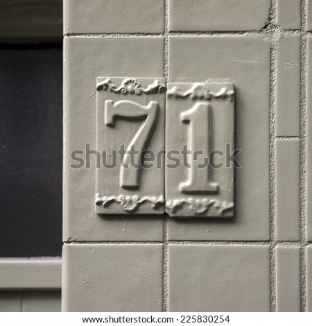 house number seventy one on two ceramic tiles. Painted over in gray.