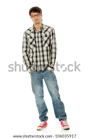 Young man standing with hands in pockets, wearing black glasses, plaid jeans and red sneakers. Isolated on the white background.