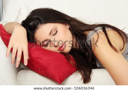 Beautiful woman is sleeping on red pillow. Pretty girl on the couch.