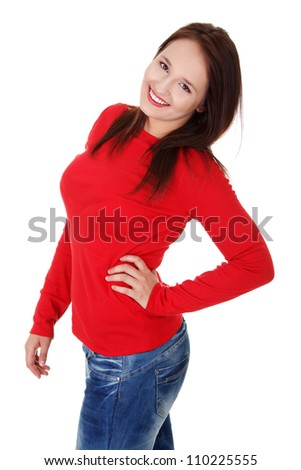 Happy young woman wearing red blouse and jeans is standing and smiling with hand on her hip. Isolated on white background.