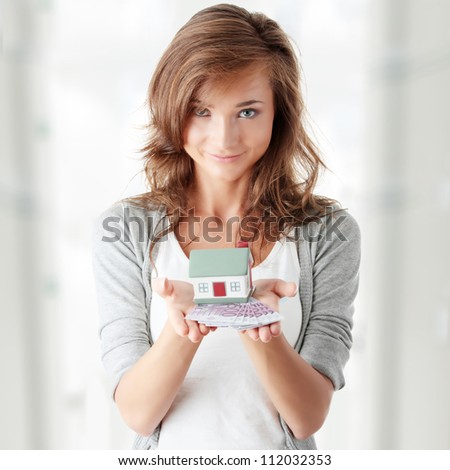 Beautiful young woman holding euros bills and house model over white - real estate loan concept