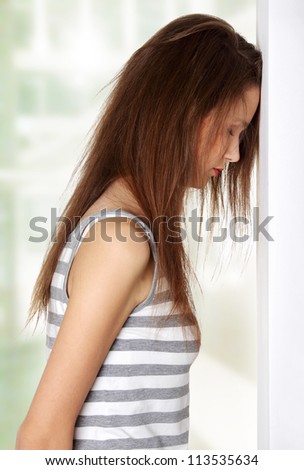 Site view of a young female teen being depressed, resting her head on a wall