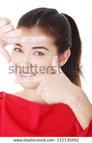 Smiling woman wearing red blouse is showing frame by hands. Happy girl with face in frame of palms. Isolated on white background.