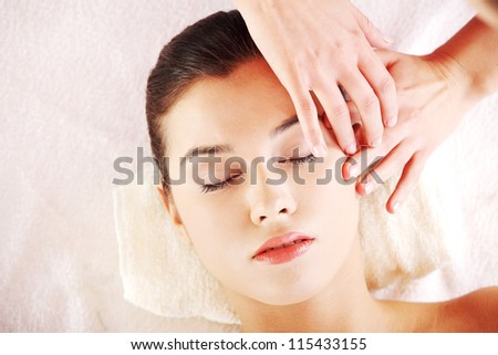 Beautiful young relaxed woman enjoy receiving face massage at spa