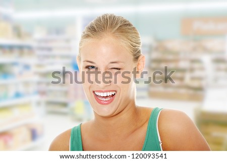 Happy young blond woman in store blinking.
