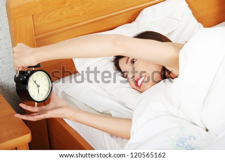 Sleepy woman in morning trying to turn off alarm clock