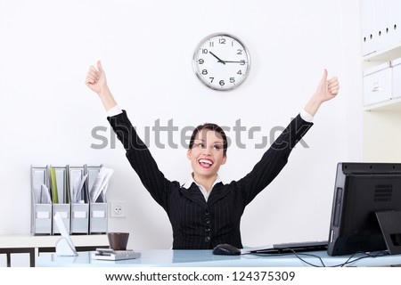 Successful attractive businesswoman with hands up at the desk in her office.
