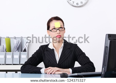 Attractive businesswoman at office with post it on her forehead.