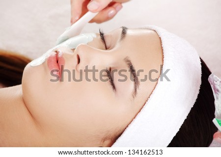 Beauty treatment in spa salon. Woman with facial clay mask.