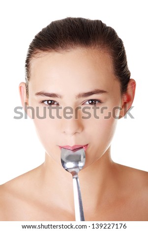 Teen girl with spoon in mouth. Isolated on white