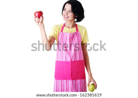 Young housewife holding apple, in kitchen apron. Isolated on white.