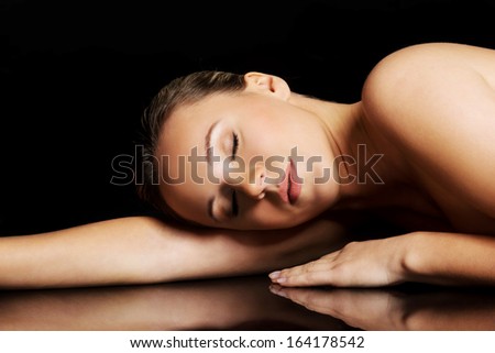 Nude woman lying on her belly. Over black background.