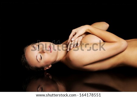 Nude woman lying on the floor. On black background.
