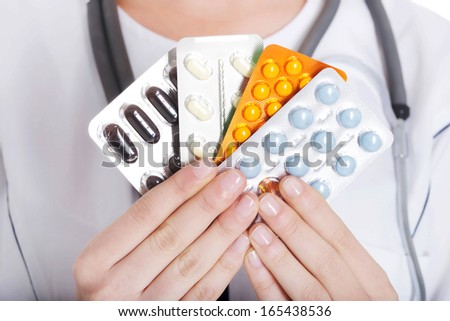 Young female doctor with pills. Isolated on white.
