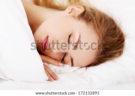 Sleeping woman lying in bed over white.
