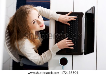 Beautiful caucasian woman sitting with hot drink and working on laptop. Up front view.