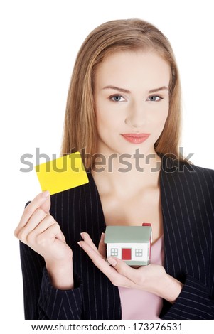 Beautiful caucasian woman is holding empty personal card and house model. Isolated on white.