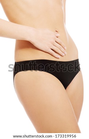 Caucasian woman is holding hand on her perfect flat belly. Isolated on white.