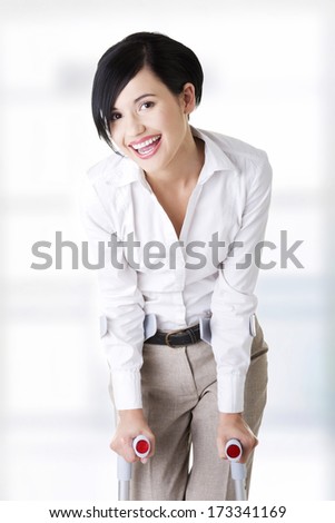 Happy young businesswoman with crutches, isolated on white. Disabled person in work.