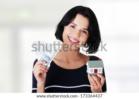 Beautiful young woman holding US dollars bills and house model over white - real estate loan concept