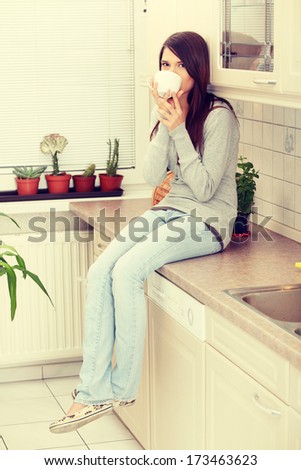 Young beautiful woman having coffee or tea in the kitchen