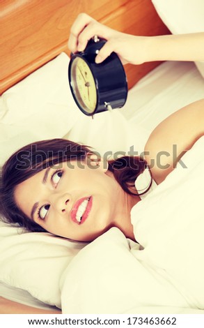 Sleepy woman in morning trying to turn off alarm clock