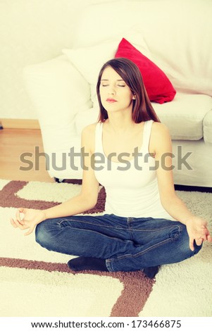 Young woman doing yoga (meditating) at home