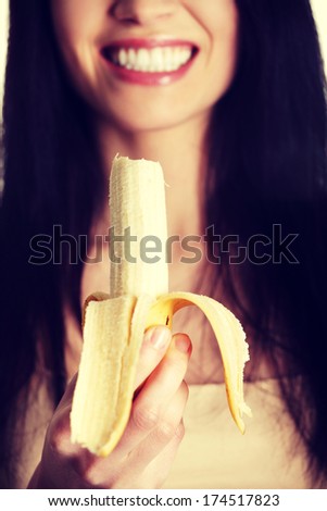 Happy beautiful young woman is eating banana.