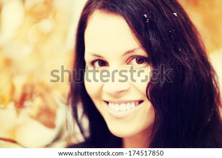 Beautiful happy woman with brown hair is smiling among fall\'s leafs. Pretty woman in autumn time.