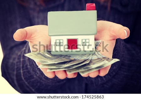 Beautiful young businesswoman holding euros bills and house model over white - real estate loan concept