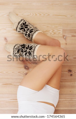 Long smooth beautiful legs with high warm socks over wooden floor.