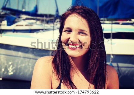 Beautiful young woman in yacht harbor. Happy girl in front of yacht boat.