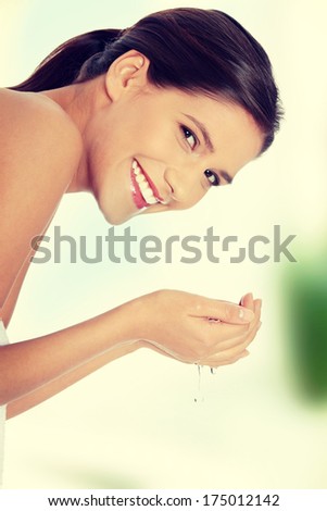Young beautiful happy female washing her face with clear water