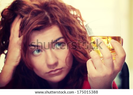 Alone young woman in depression, drinking alcohol (burbon)