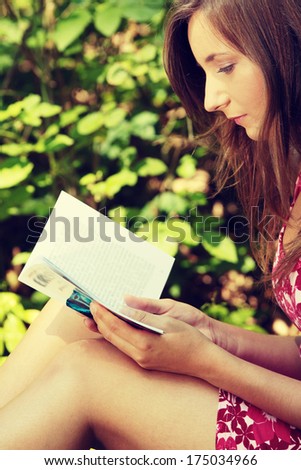 Reading woman sitting in a park bench in summer.