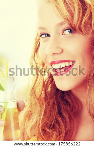Young beautiful blond woman sipping cocktail (green ice tea)