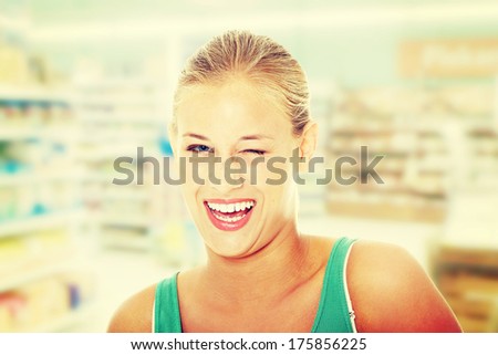 Happy young blond woman in store blinking.