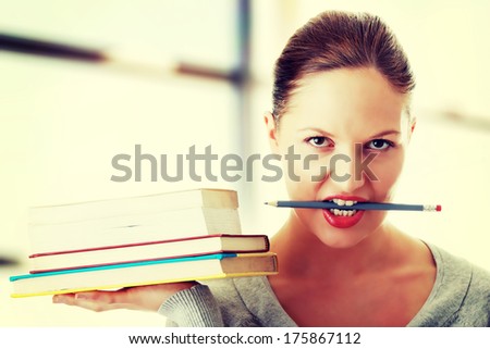 Young caucasian student with books on hand and pencil in mouth