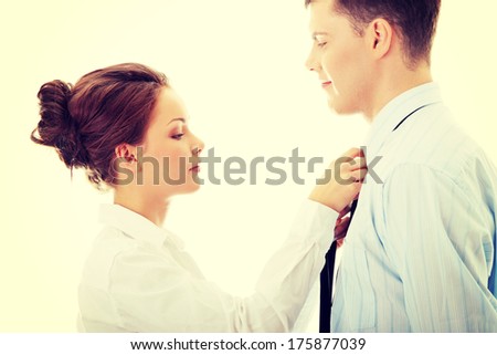 Businesswoman knotting the necktie of the businessman, helping and assisting him getting dressed.
