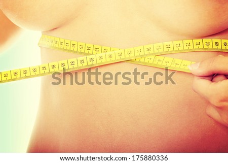 Naked belly of sexy, fit, young woman measuring her waist