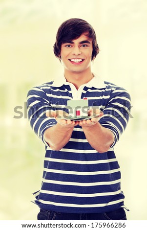 Young man with money and house\'s model.