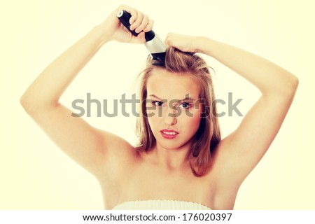 Young teen woman cutting her long hais with hair clipper
