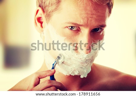 Young caucasian man is shaving hisself