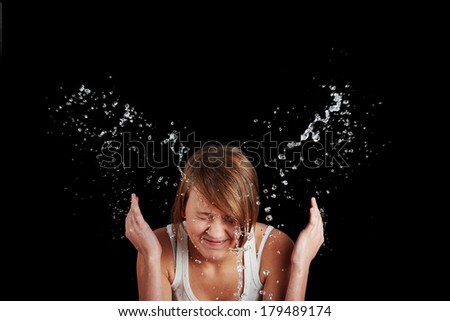 Teen girl washing her face with water, isolated on black