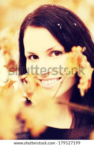 Beautiful woman with brown hair is smiling among fall\'s leafs. Pretty woman in autumn time.