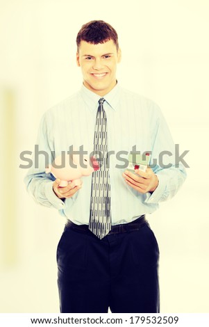 Young business person encourage saving money. Holding house model and piggy bank