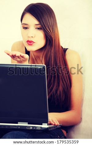 Young woman\'s sending kiss to laptop. In home.