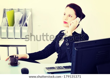 Pretty caucasian businesswoman answering the phone in the office.