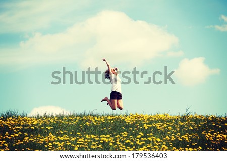 Happy woman jumping on blossom meadow. Beautiful day on field.