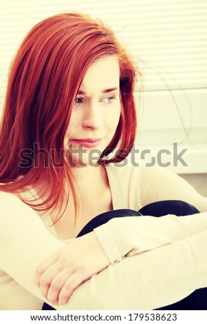 A worried and afraid young woman sitting on the flor.